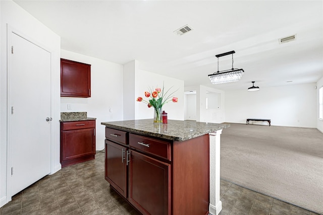 kitchen with visible vents, open floor plan, and reddish brown cabinets