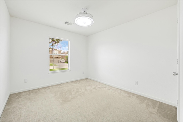 spare room with baseboards, light carpet, and visible vents