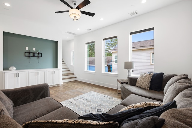 living area with a ceiling fan, visible vents, stairs, light wood finished floors, and recessed lighting