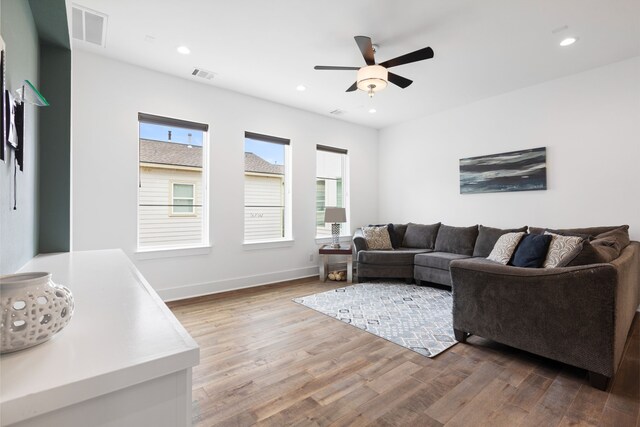 living room with ceiling fan, wood finished floors, and visible vents