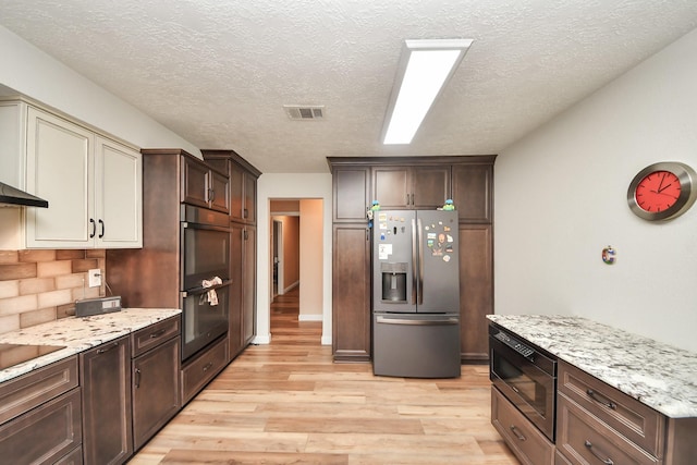 kitchen featuring dobule oven black, visible vents, stainless steel refrigerator with ice dispenser, light wood-type flooring, and built in microwave