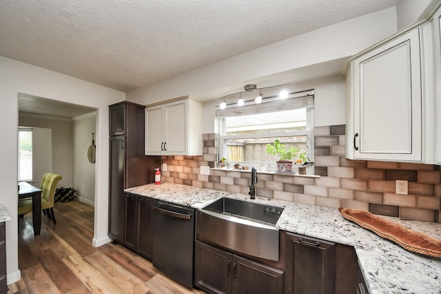 kitchen with tasteful backsplash, dark brown cabinets, a sink, light wood-style floors, and black dishwasher