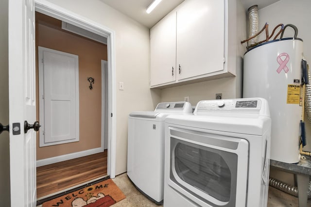 clothes washing area with baseboards, washer and clothes dryer, cabinet space, and electric water heater