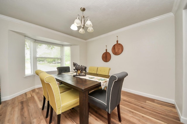 dining room with crown molding, baseboards, light wood-style flooring, and a notable chandelier