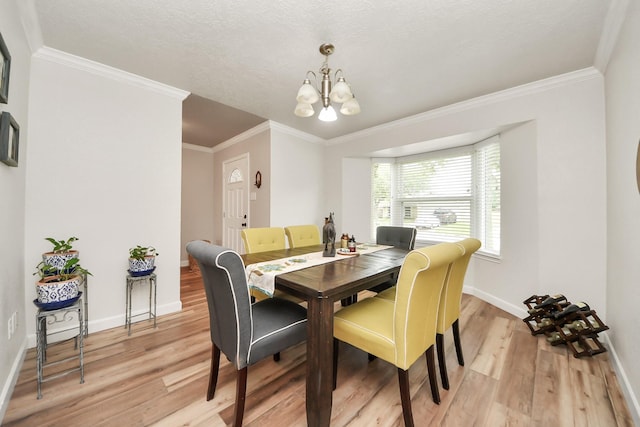 dining space featuring crown molding, baseboards, light wood-type flooring, and a notable chandelier