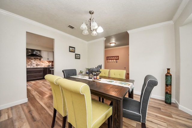 dining area with visible vents, a notable chandelier, ornamental molding, and light wood finished floors