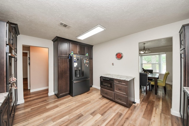 kitchen featuring dark brown cabinetry, visible vents, fridge with ice dispenser, light wood finished floors, and a chandelier