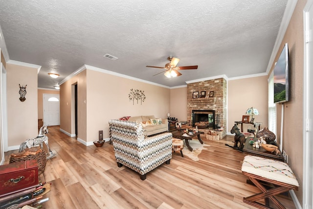 living room with visible vents, a fireplace, a textured ceiling, a ceiling fan, and light wood finished floors