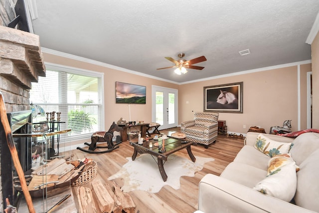 living area featuring crown molding, a textured ceiling, a ceiling fan, wood finished floors, and visible vents