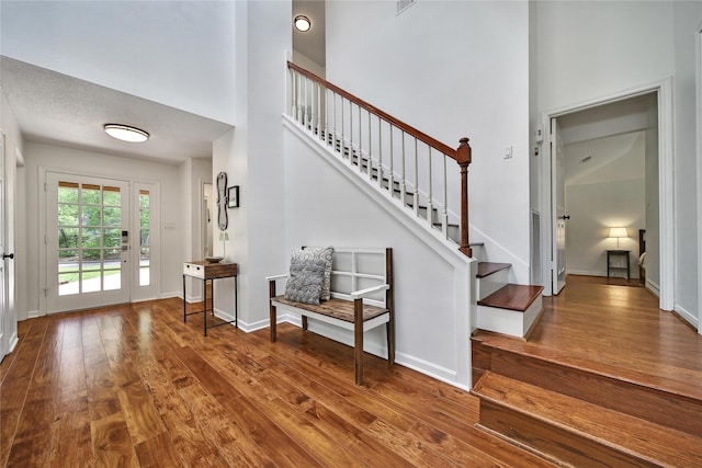 entryway with baseboards, a high ceiling, wood-type flooring, and stairs