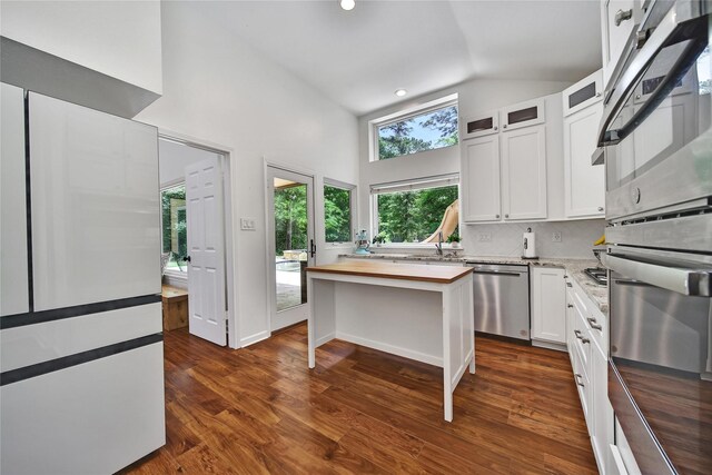 kitchen with dark wood-style flooring, appliances with stainless steel finishes, butcher block countertops, white cabinetry, and glass insert cabinets