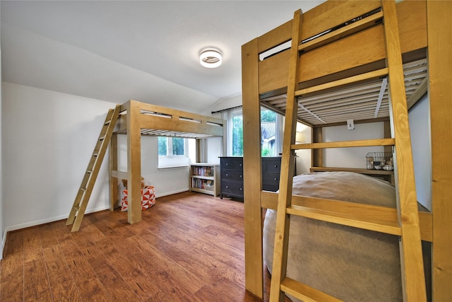 bedroom featuring baseboards, lofted ceiling, and wood finished floors