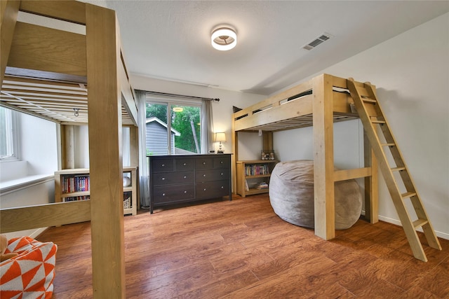 bedroom featuring wood finished floors and visible vents