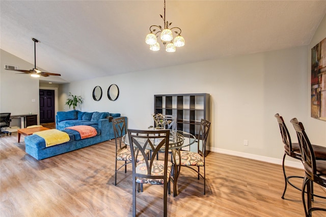 dining area featuring visible vents, lofted ceiling, baseboards, light wood-style flooring, and ceiling fan with notable chandelier