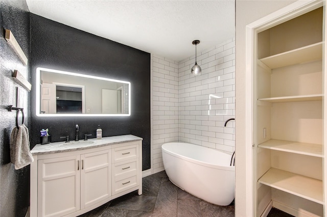bathroom featuring vanity, a walk in closet, walk in shower, a textured ceiling, and a soaking tub