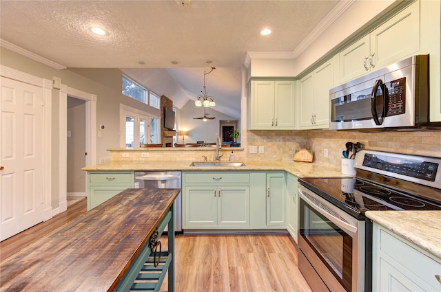 kitchen with appliances with stainless steel finishes, a sink, light wood finished floors, and green cabinets