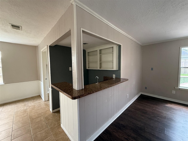 kitchen featuring visible vents, ornamental molding, a textured ceiling, and baseboards