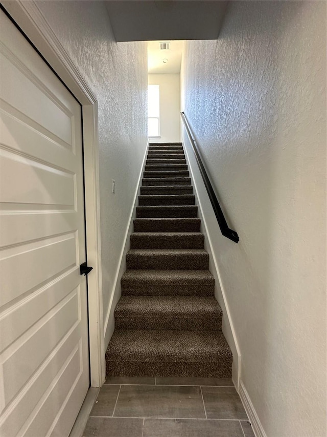 507 Kickapoo Dr, Anahuac, TX 77514 - staircase with visible vents, a textured wall, and baseboards