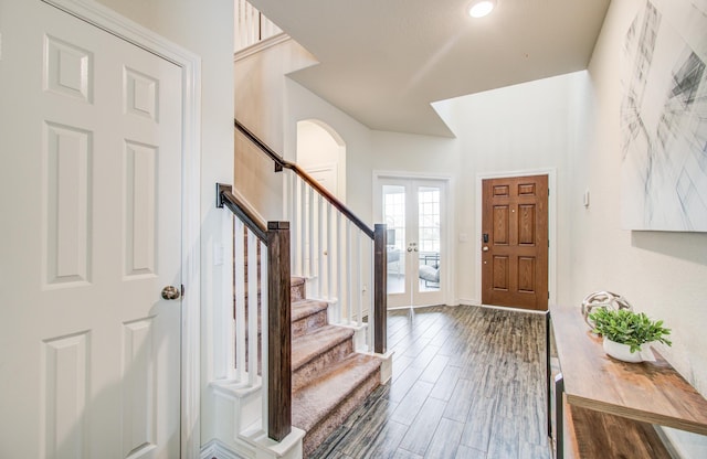 foyer with arched walkways, baseboards, stairs, and dark wood-type flooring