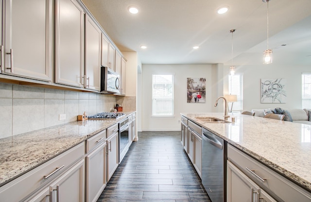 kitchen with a sink, stainless steel appliances, baseboards, decorative light fixtures, and backsplash