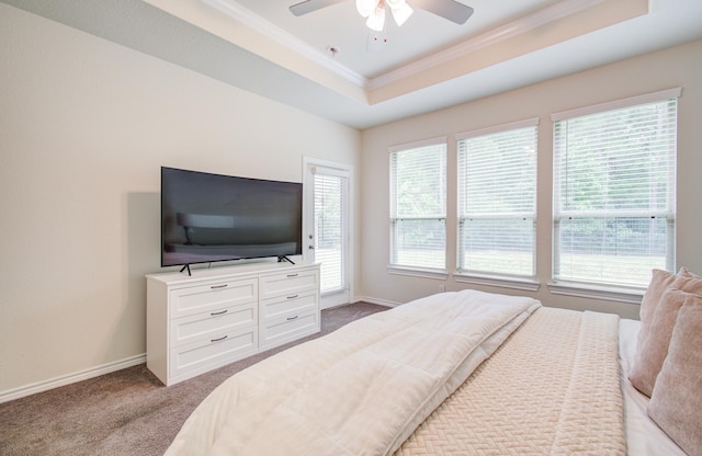 carpeted bedroom featuring a tray ceiling, ceiling fan, ornamental molding, and baseboards