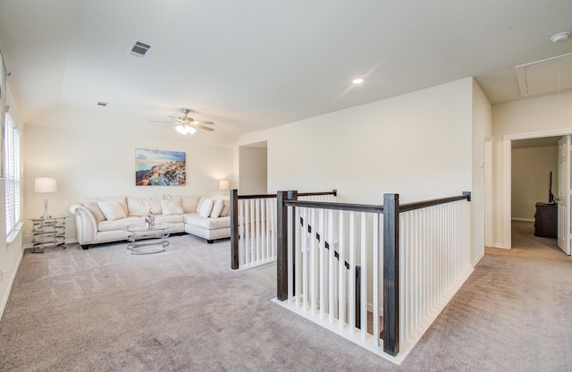 living area featuring visible vents, baseboards, attic access, a ceiling fan, and carpet