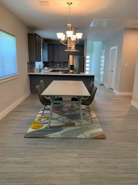1019 E 37th St, Houston, TX 77022 - dining space featuring baseboards, an inviting chandelier, and light wood-type flooring