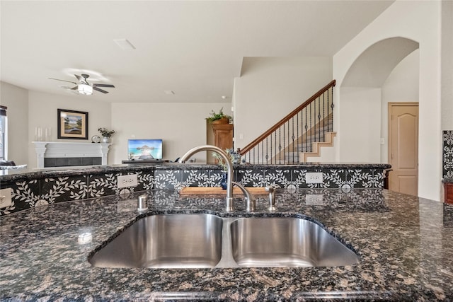 28406 Green Mill Ct, Spring, TX 77386 - interior details with a sink, dark stone counters, ceiling fan, and a fireplace