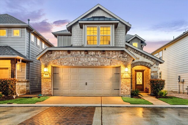 craftsman house featuring brick siding, a garage, driveway, and a standing seam roof