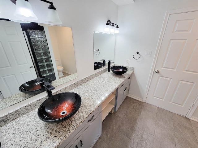 5703 Fraser Ave, Galveston, TX 77551 - full bathroom featuring baseboards, a sink, double vanity, and toilet