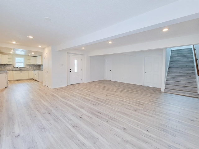 5703 Fraser Ave, Galveston, TX 77551 - unfurnished living room with stairs, recessed lighting, a sink, and light wood-style floors