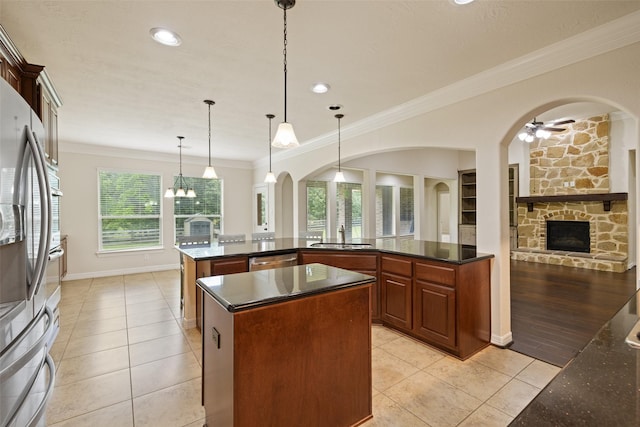 kitchen featuring a center island, appliances with stainless steel finishes, light tile patterned flooring, and a stone fireplace