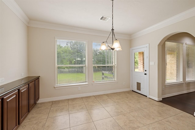 unfurnished dining area featuring visible vents, arched walkways, crown molding, and a healthy amount of sunlight
