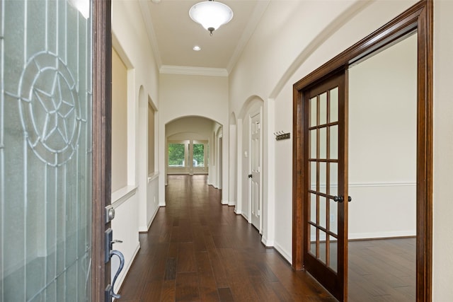 hallway featuring ornamental molding, dark wood-style flooring, baseboards, french doors, and arched walkways