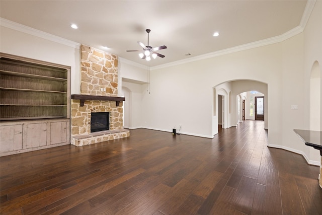 unfurnished living room featuring a ceiling fan, arched walkways, a fireplace, and ornamental molding