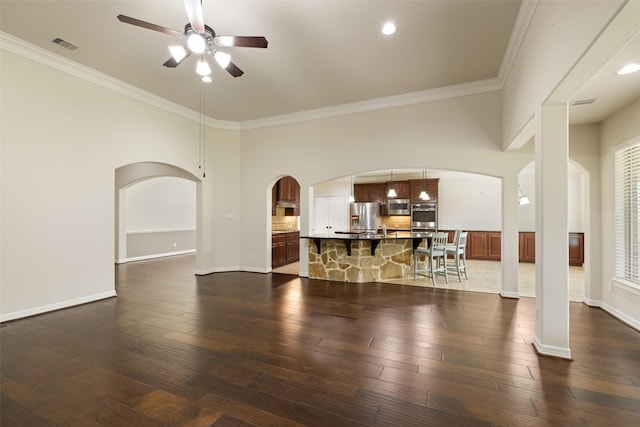 living room with crown molding, arched walkways, ceiling fan, and visible vents