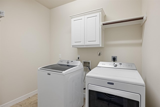 clothes washing area with baseboards, cabinet space, and washing machine and dryer