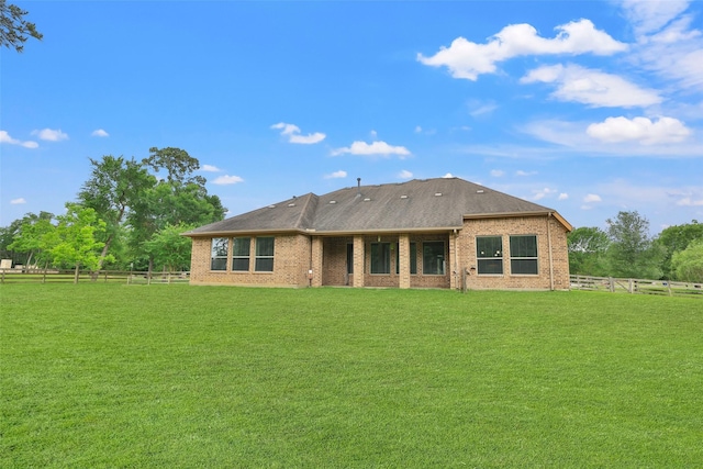 rear view of property featuring a yard, brick siding, and fence