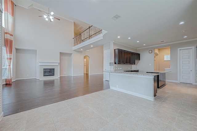kitchen featuring visible vents, ornamental molding, light tile patterned flooring, ceiling fan, and arched walkways