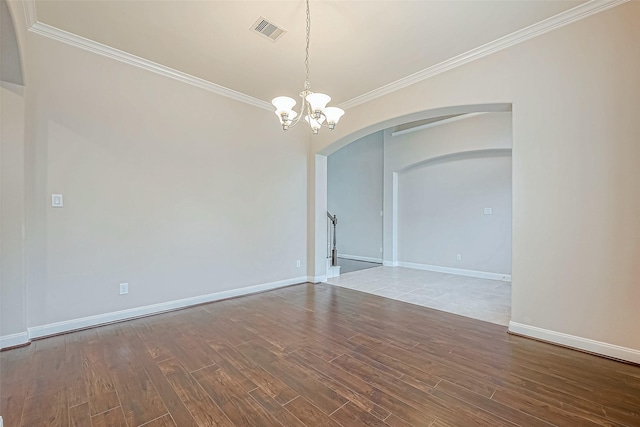unfurnished room with a notable chandelier, arched walkways, wood finished floors, visible vents, and ornamental molding