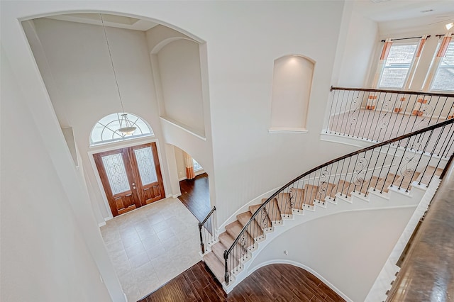 foyer featuring arched walkways, a high ceiling, wood finished floors, and stairway