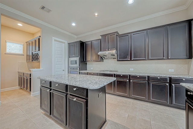 kitchen with decorative backsplash, a kitchen island, visible vents, light stone counters, and stainless steel appliances