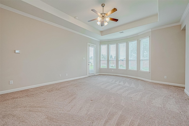 spare room featuring crown molding, ceiling fan, light carpet, a raised ceiling, and baseboards
