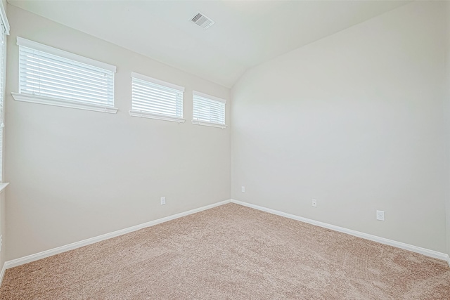 unfurnished room with carpet flooring, baseboards, visible vents, and vaulted ceiling