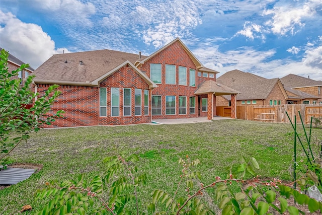 rear view of property with a fenced backyard, a yard, a patio area, and brick siding