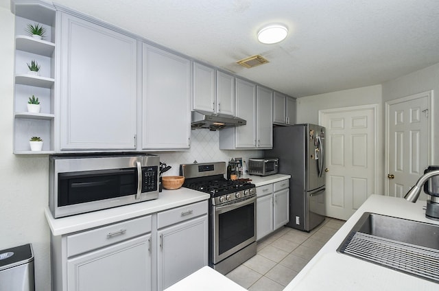 kitchen featuring under cabinet range hood, stainless steel appliances, open shelves, and a sink