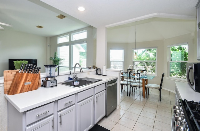 kitchen with stainless steel appliances, light tile patterned floors, a wealth of natural light, and a sink