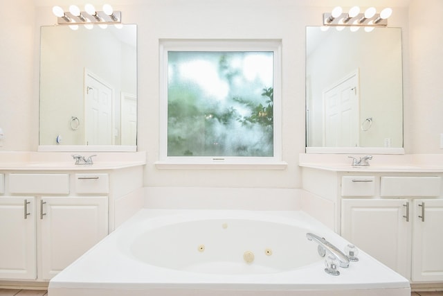 bathroom with a sink, plenty of natural light, a tub with jets, and two vanities