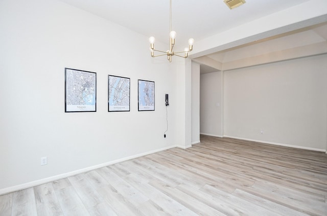 spare room with an inviting chandelier, baseboards, light wood-style flooring, and visible vents