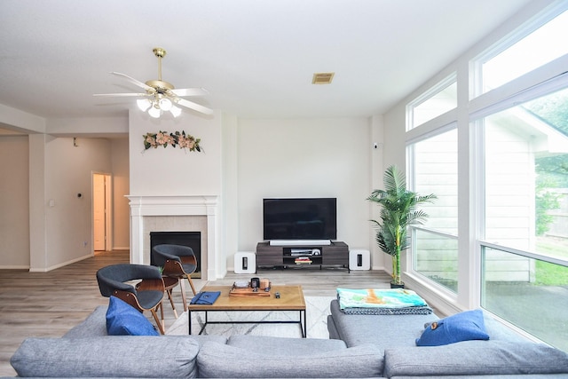 living area with visible vents, wood finished floors, a wealth of natural light, and a fireplace